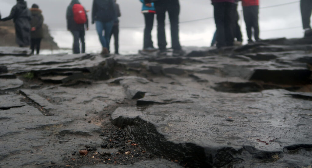 Tourists in rain gear alongside Gulfoss at the end of its lower viewing path.