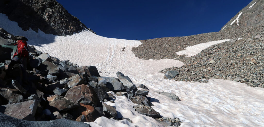 Heading up snow and talus towards the upper basin.