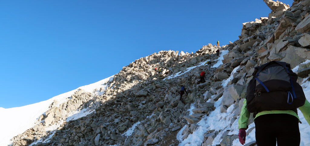 Hikers scrambling up the backside of Snowmass.