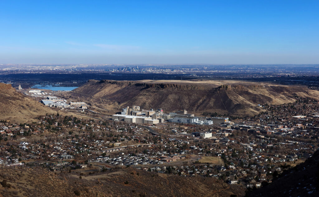 The town of Golden, and the famous Coors factory in the foreground, with North Table Mountain immediately behind. Further afield, the high rises of downtown Denver poke up near the horizon.